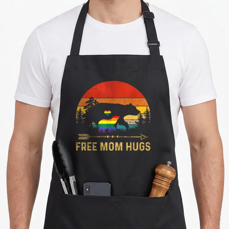 Free cute bear apron - Rainbow bears and free mom hugs text on black apron — shown on a black cotton canvas apron against a white background