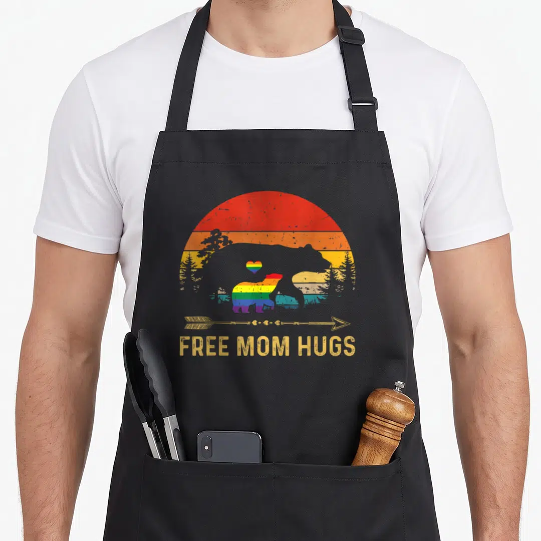 Free cute bear apron - Rainbow bears and free mom hugs text on black apron — shown on a black cotton canvas apron against a white background