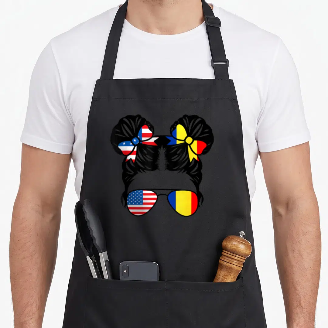 Romania flag romanian apron - Cartoon messy bun with US and Romania flag bows and sunglasses in black red white blue — shown on a black cotton canvas apron against a white background