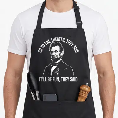 They theater apron - White distressed Abraham Lincoln portrait with arched and straight text quotes — shown on a black cotton canvas apron against a white background