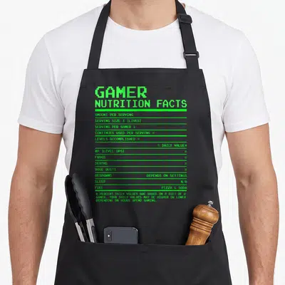 Nutrition video game apron - Green pixel text listing 0 frags, 0 deaths, and fuel as pizza and soda on a grey background — shown on a black cotton canvas apron against a white background