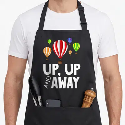 Away balloon apron - Five striped hot air balloons floating above white text reading UP, UP AND AWAY — shown on a black cotton canvas apron against a white background