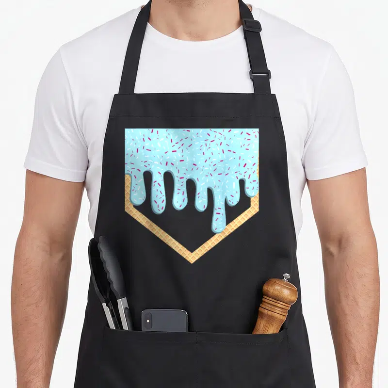 Youth birthday ice cream apron - Cartoon waffle home plate with light blue icing and red white sprinkles — shown on a black cotton canvas apron against a white background