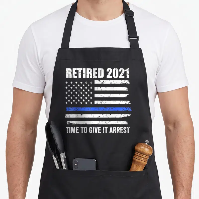 Retirement american flag apron - Distressed white and blue flag with retired 2021 and time to give it arrest text — shown on a black cotton canvas apron against a white background