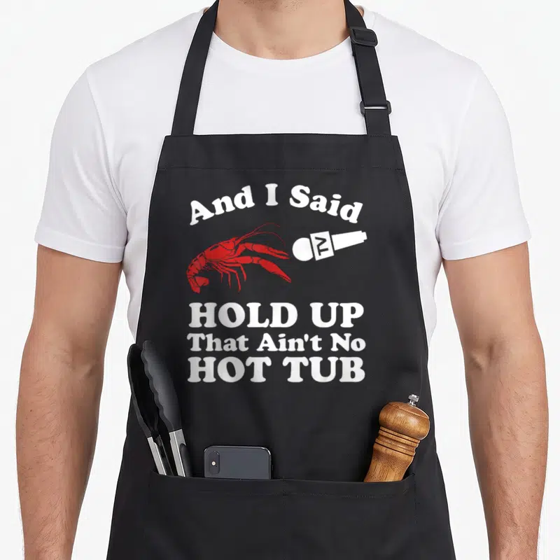 Hot cajun aprons - Red lobster facing white microphone with arched text And I Said Hold Up That Ain't No Hot Tub — shown on a black cotton canvas apron against a white background