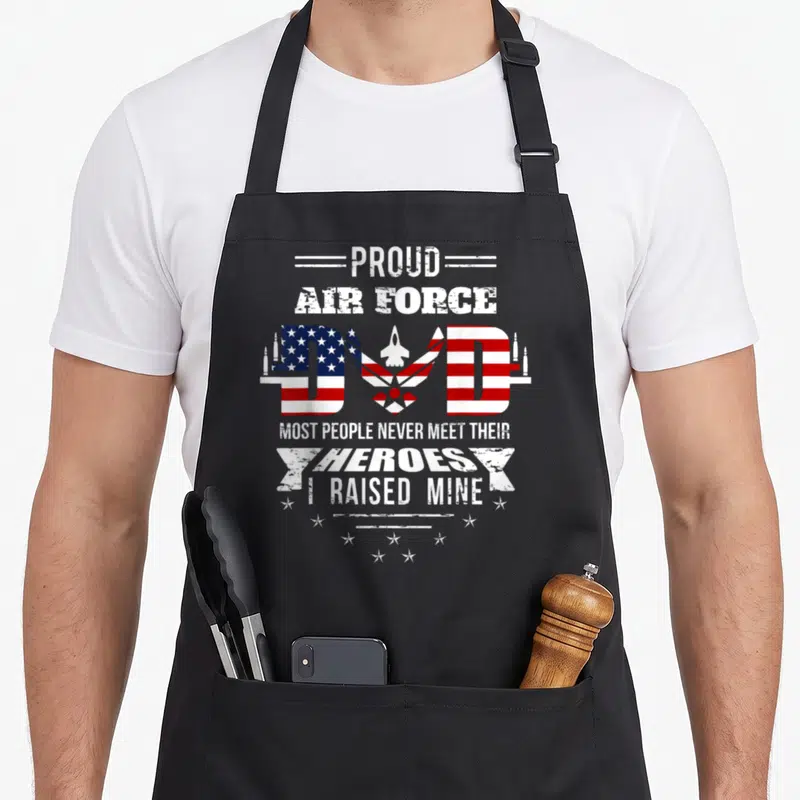 Proud air dad apron - Distressed red white and blue text reading proud air force dad most people never meet — shown on a black cotton canvas apron against a white background