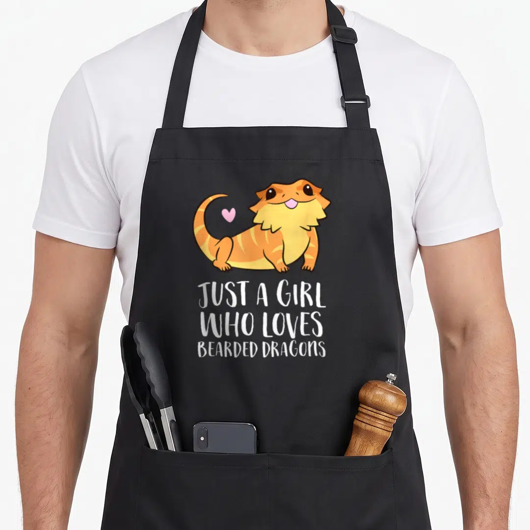 Reptile dragon apron - Cartoon orange bearded dragon with pink heart and white text — shown on a black cotton canvas apron against a white background