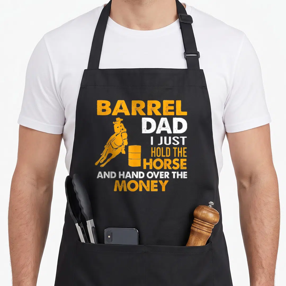 Hold horse apron - Orange and white distressed text reading Barrel Dad I Just Hold The Horse And Hand Over The Money — shown on a black cotton canvas apron against a white background