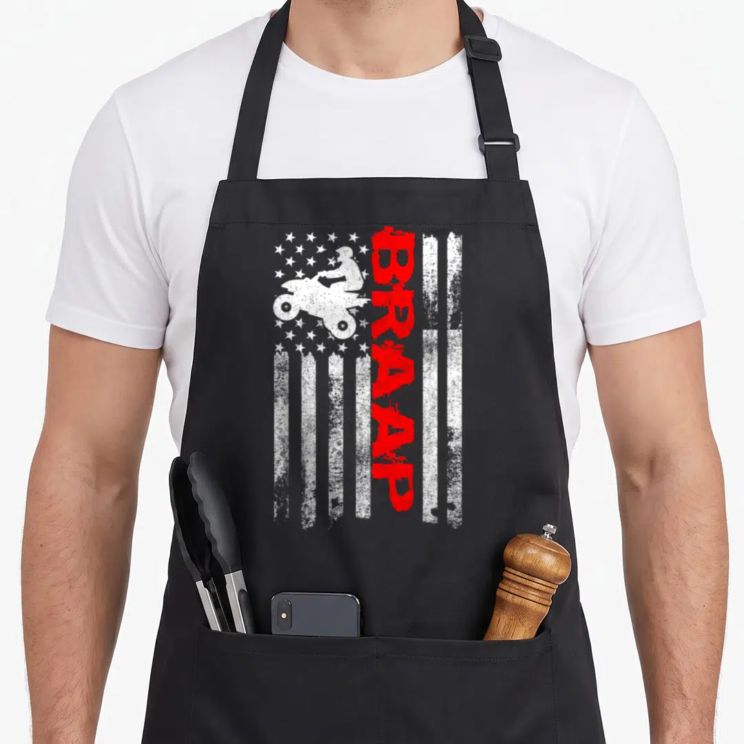 Wheeler american flag apron - Distressed white flag with quad bike silhouette and vertical red BRAAP text — shown on a black cotton canvas apron against a white background