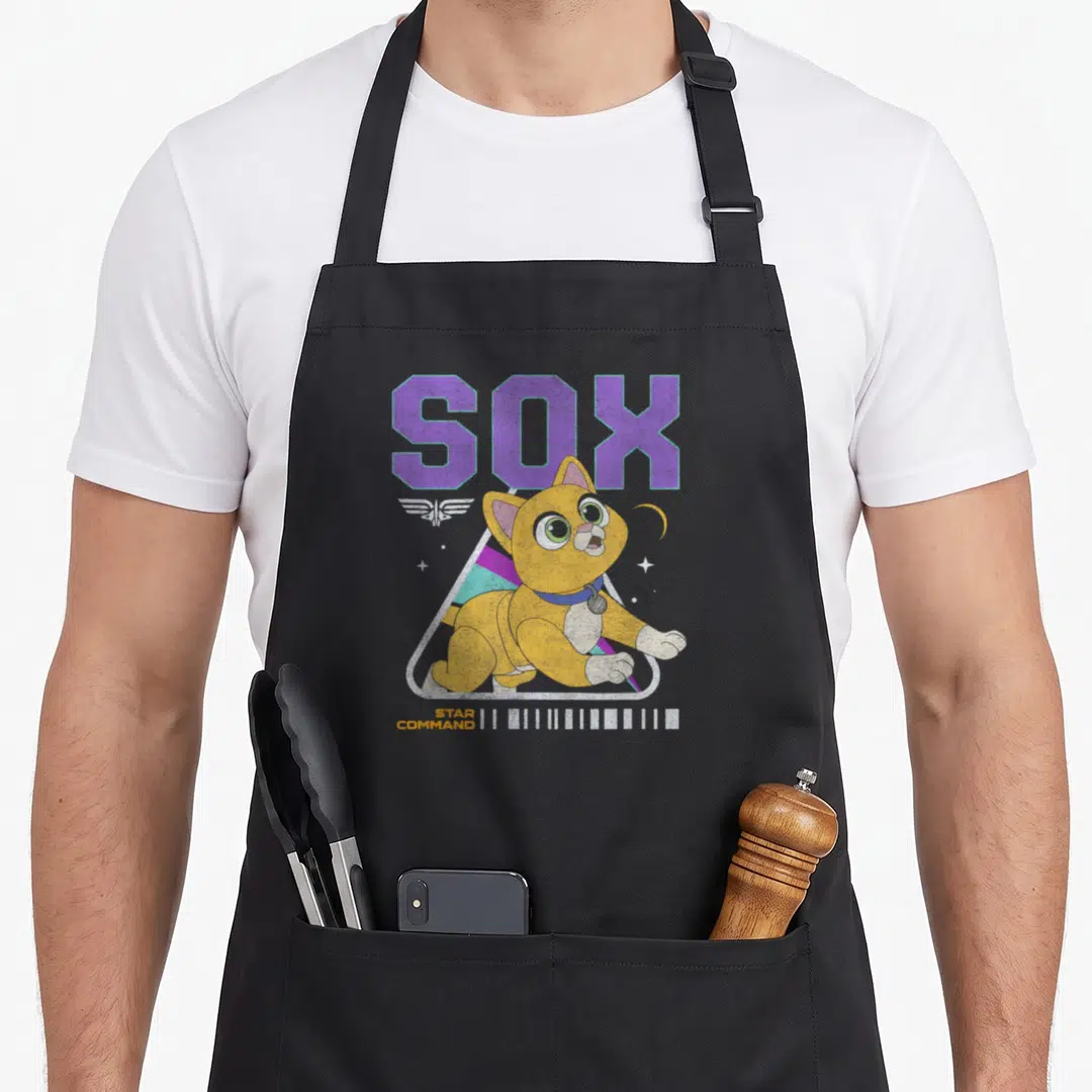 Sox cat apron - Yellow cartoon cat in purple orange triangle with SOX STAR COMMAND text and barcode — shown on a black cotton canvas apron against a white background