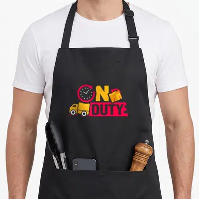 Duty food aprons - ON DUTY text with clock, package, and truck in red, yellow, white cartoon style — shown on a black cotton canvas apron against a white background