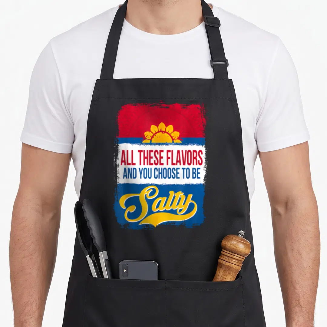 These sunflower apron - Yellow sun on red and blue background with text ALL THESE FLAVORS AND YOU CHOOSE TO BE Salty — shown on a black cotton canvas apron against a white background