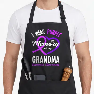 Memory grandma apron - Purple ribbon overlapping a heart with I Wear Purple in Memory of my Grandma text — shown on a black cotton canvas apron against a white background