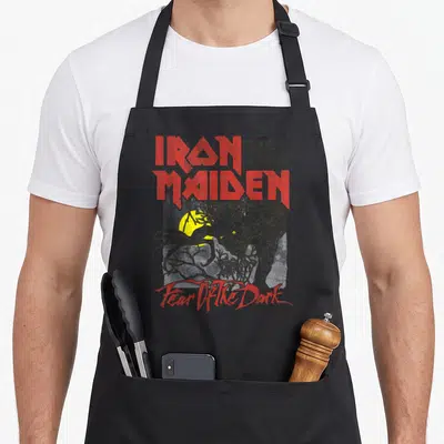 Fear lemon apron - Red Iron Maiden lettering above a grey monster and yellow moon in distressed style — shown on a black cotton canvas apron against a white background