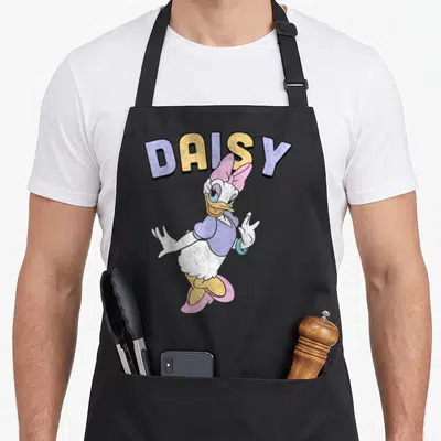 Simple daisy apron - Arched DAISY text above cartoon duck with outstretched hands in purple, yellow, pink, and white — shown on a black cotton canvas apron against a white background