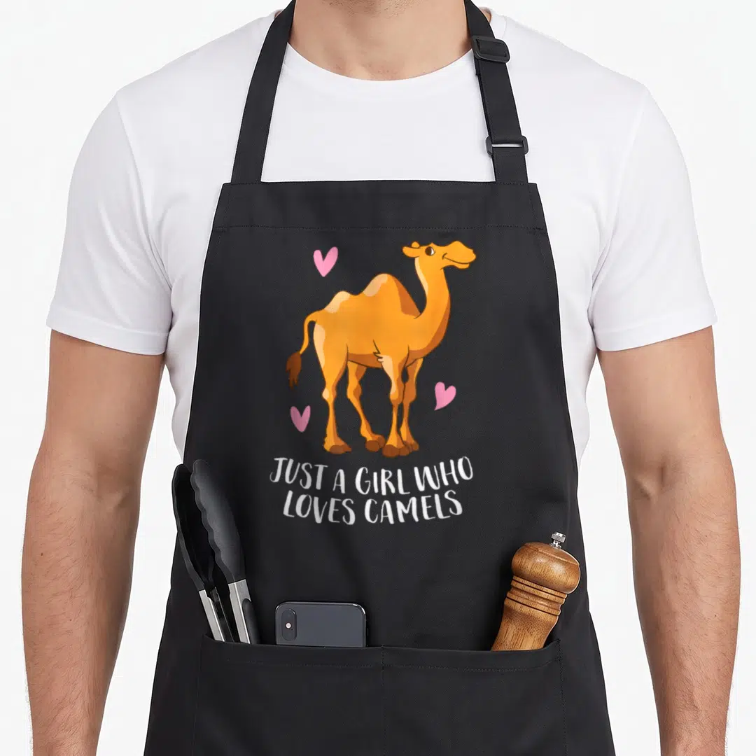 Cute camel apron - Cartoon orange camel with three pink hearts and white text below — shown on a black cotton canvas apron against a white background