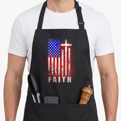 Patriotic funny christian aprons - Distressed red white blue flag with white cross and FAITH text — shown on a black cotton canvas apron against a white background