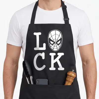 Funny lucky st patrick day aprons - White text LOCK with Spider-Man mask replacing the letter O in minimalist style — shown on a black cotton canvas apron against a white background