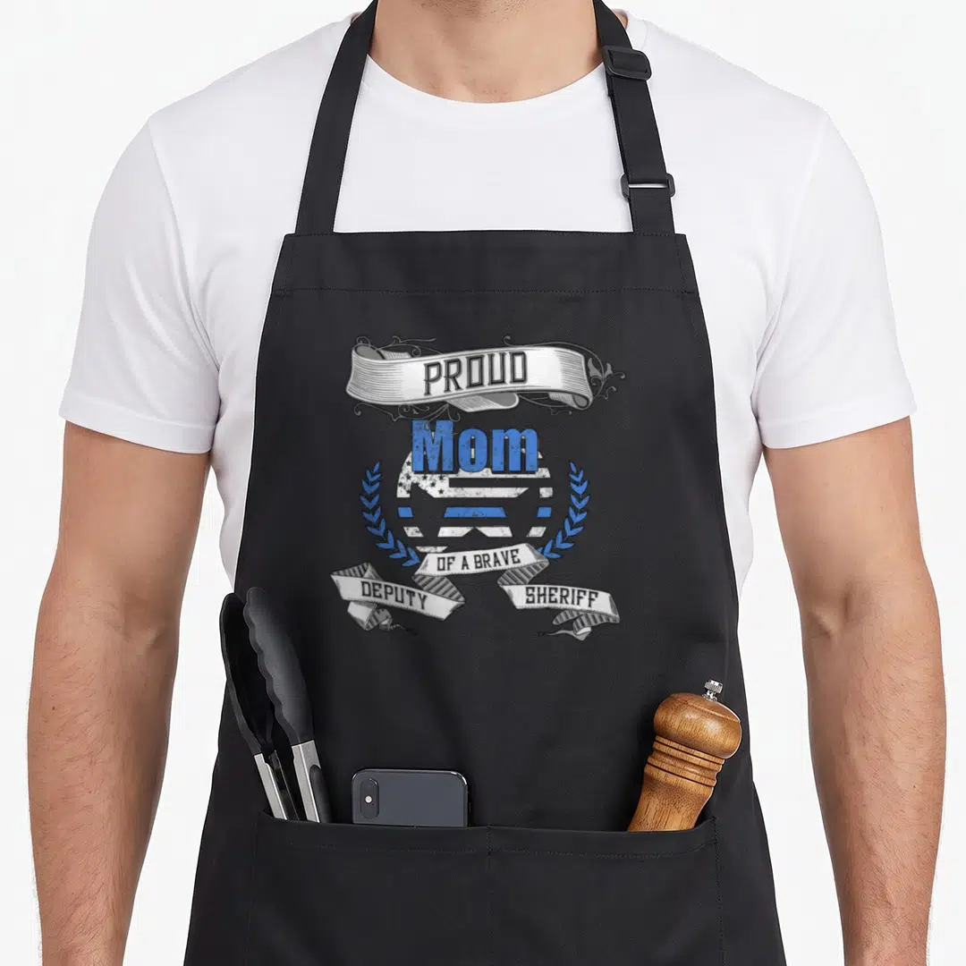 Deputy badger mom apron - Retro blue white and black ribbon art reading Proud Mom of a Brave Deputy Sheriff flanked — shown on a black cotton canvas apron against a white background
