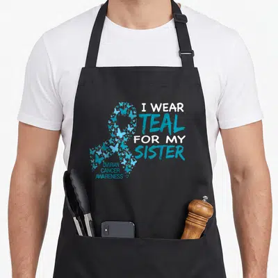 Sister lover mothers apron - Teal and white text I Wear Teal For My Sister beside butterfly awareness ribbon — shown on a black cotton canvas apron against a white background