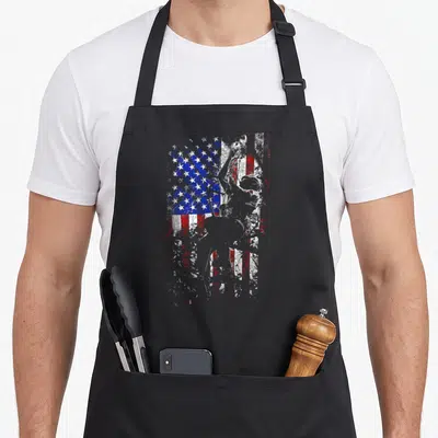 Tool surgeon apron - Distressed USA flag background with a silhouetted person figure in red white and blue — shown on a black cotton canvas apron against a white background