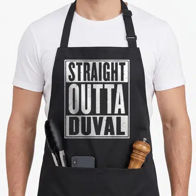 Straight jacksonville apron - White distressed text reading STRAIGHT OUTTA DUVAL stacked in a rectangle — shown on a black cotton canvas apron against a white background