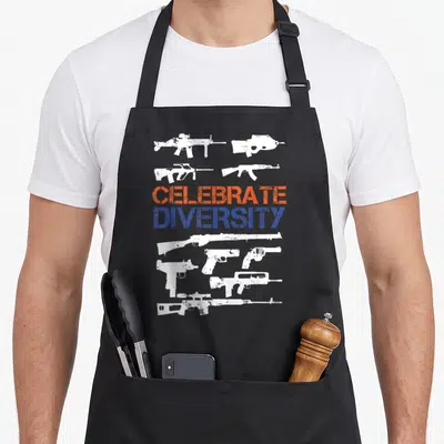 Diversity gun apron - Nine distressed white guns surrounding orange and blue CELEBRATE DIVERSITY text on black bib apron — shown on a black cotton canvas apron against a white background