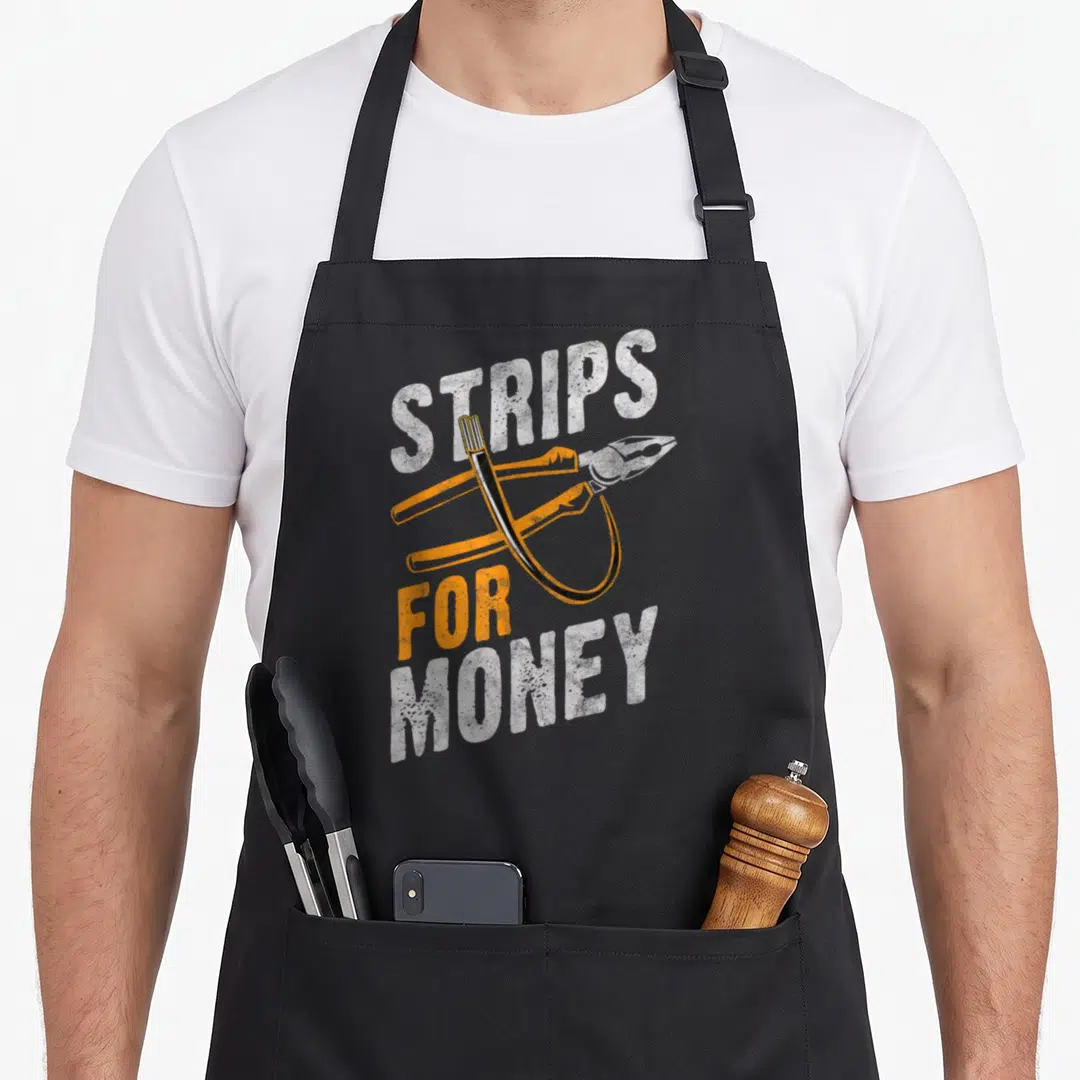 Powerline electrician apron - STRIPS FOR MONEY text with wire strippers and looped wire in white orange black — shown on a black cotton canvas apron against a white background