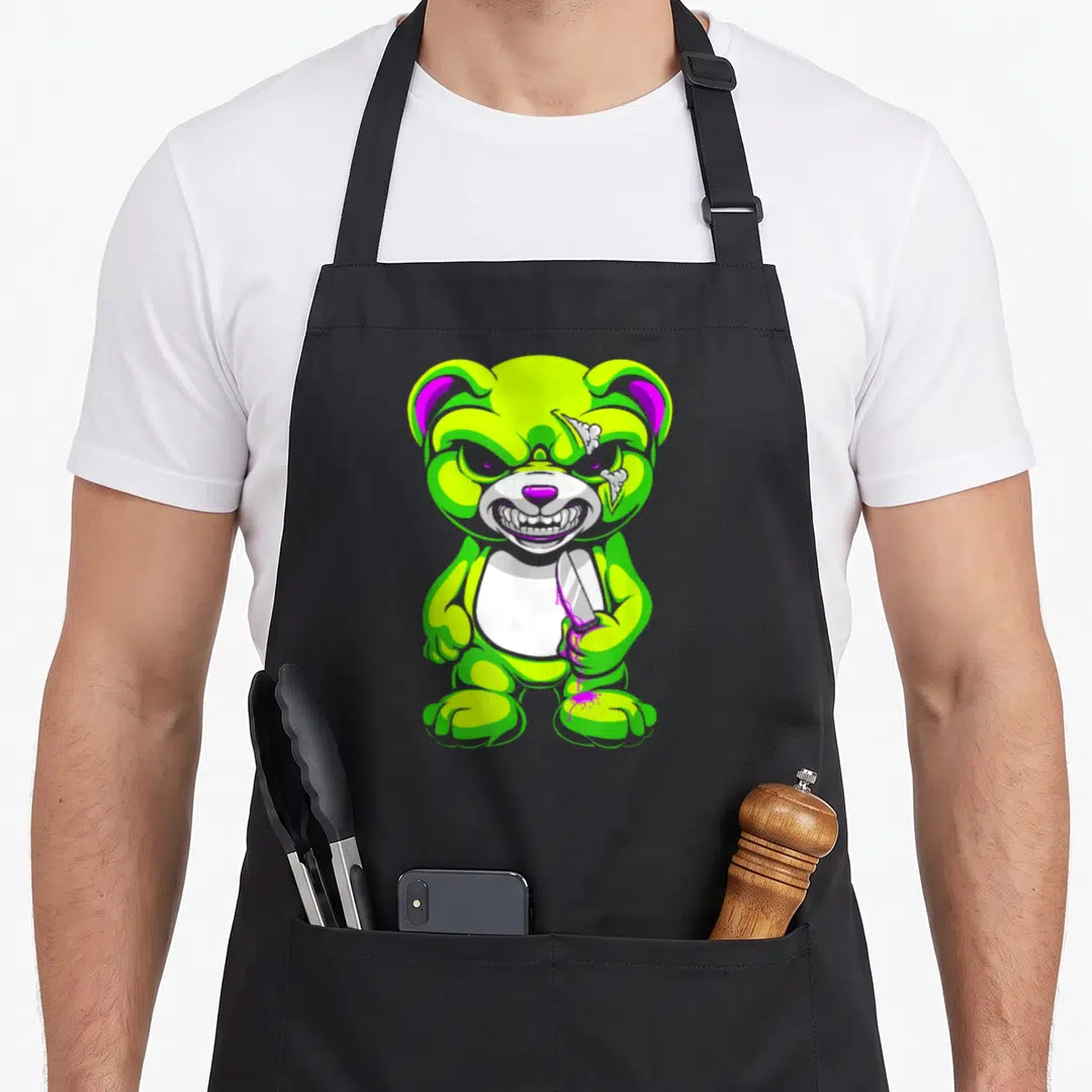 Goth teddy bear apron - Lime green cartoon bear holding a knife with purple liquid dripping from the blade — shown on a black cotton canvas apron against a white background