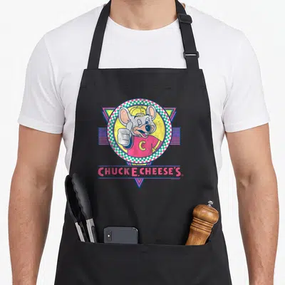 Winking e.a apron - Winking mouse thumbs up in checkered circle with CHUCK E. CHEESE'S text — shown on a black cotton canvas apron against a white background