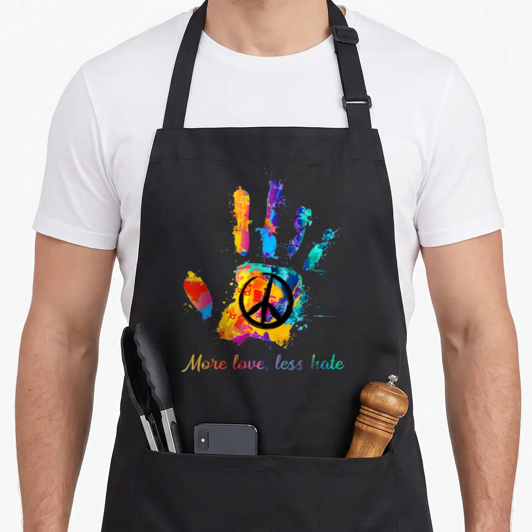 Hippie handprint apron - Multicolored watercolor hand with black peace sign and rainbow text — shown on a black cotton canvas apron against a white background