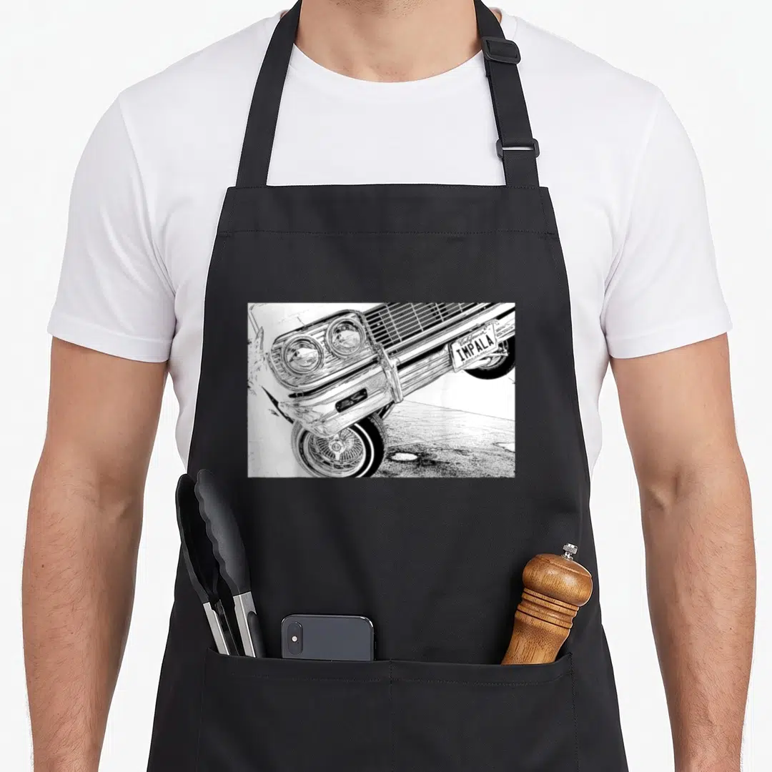 Impala wheel apron - Black and white line art of a classic car front with California Impala license plate and wire wheel — shown on a black cotton canvas apron against a white background