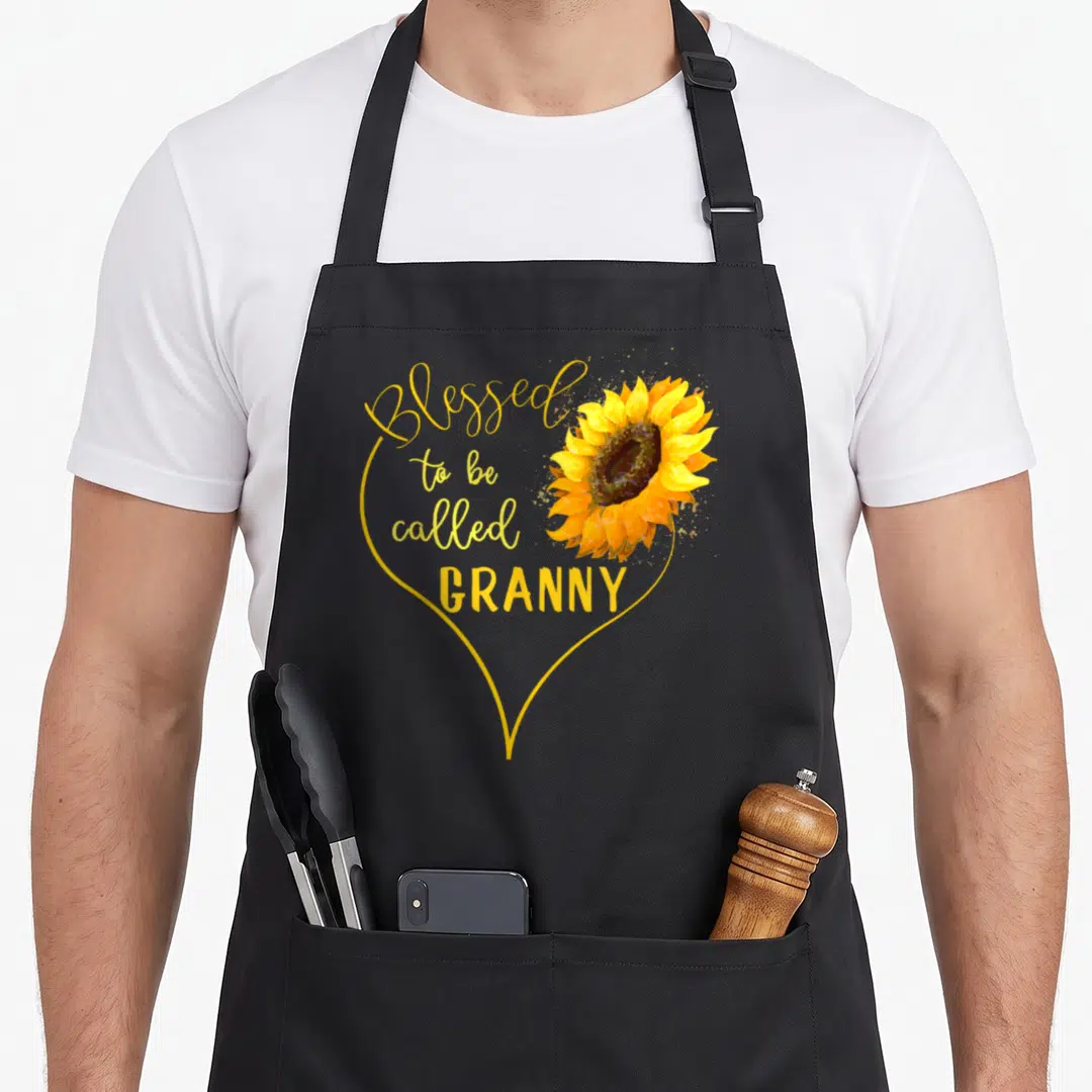 Sunflower granny apron - Yellow heart outline with text Blessed to be called GRANNY and watercolor sunflower — shown on a black cotton canvas apron against a white background