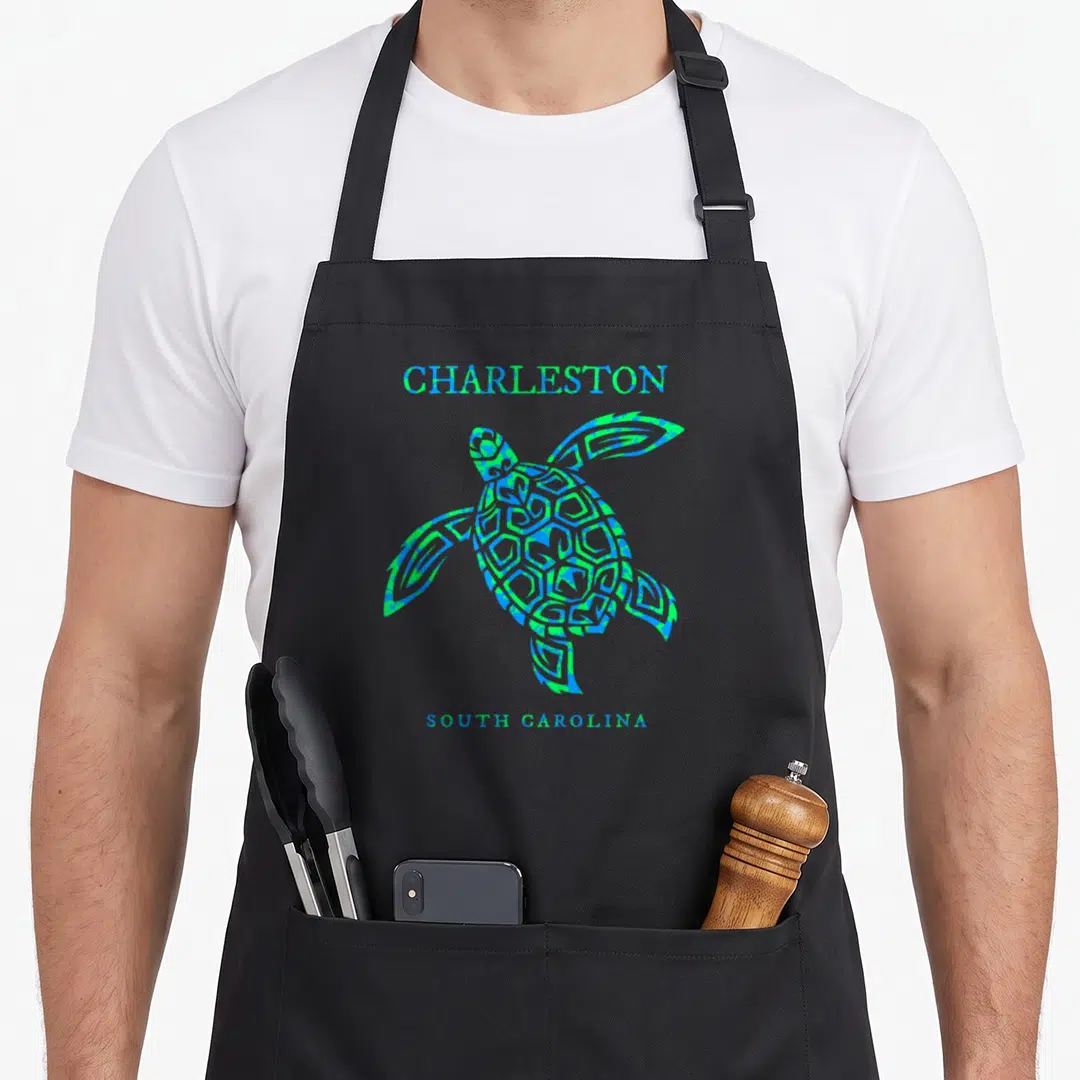 Turtle charleston apron - Graphic sea turtle in blue and green with Charleston South Carolina text — shown on a black cotton canvas apron against a white background