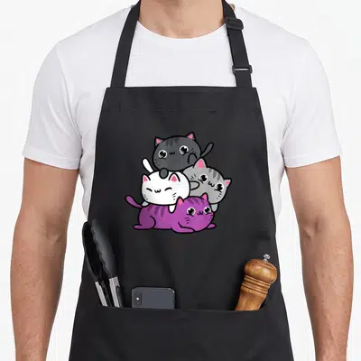 Pile kawaii apron - Three cartoon cats stacked pyramid shape in grey white purple black kawaii style — shown on a black cotton canvas apron against a white background