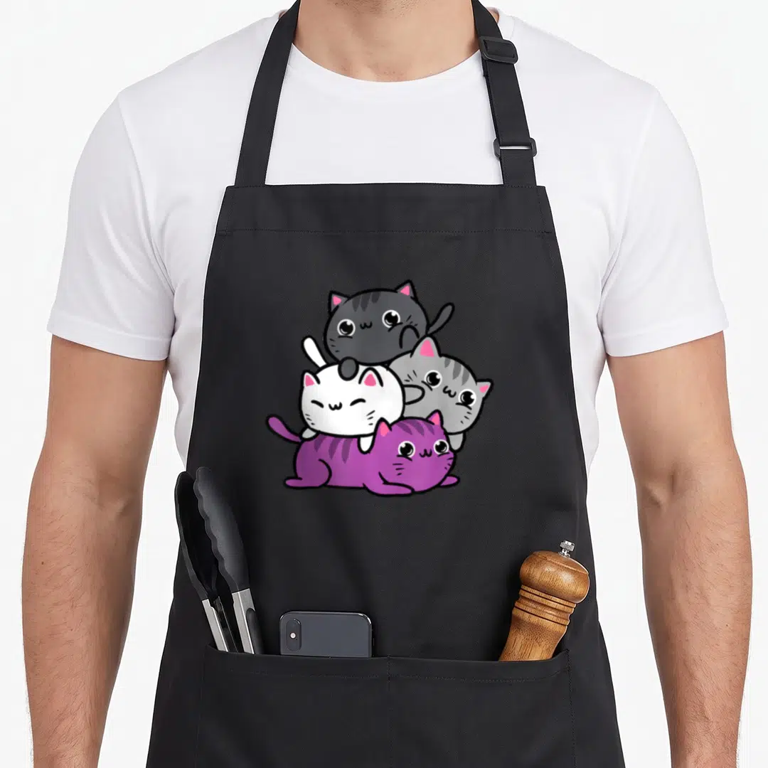 Pile kawaii apron - Three cartoon cats stacked pyramid shape in grey white purple black kawaii style — shown on a black cotton canvas apron against a white background