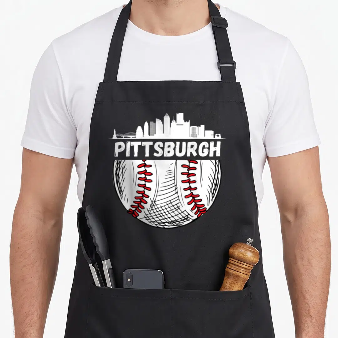Pittsburgh baseball apron - Distressed PITTSBURGH text between white skyline and partial baseball with red laces — shown on a black cotton canvas apron against a white background