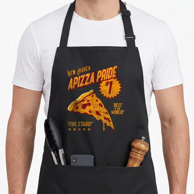 Apizza pizza apron - Distressed orange pizza slice with New Haven Apizza Pride text and five stars — shown on a black cotton canvas apron against a white background