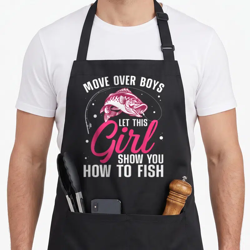 Cute fishing fisherman apron - Pink and white bass graphic with text Move Over Boys Let This Girl Show You How To Fish — shown on a black cotton canvas apron against a white background