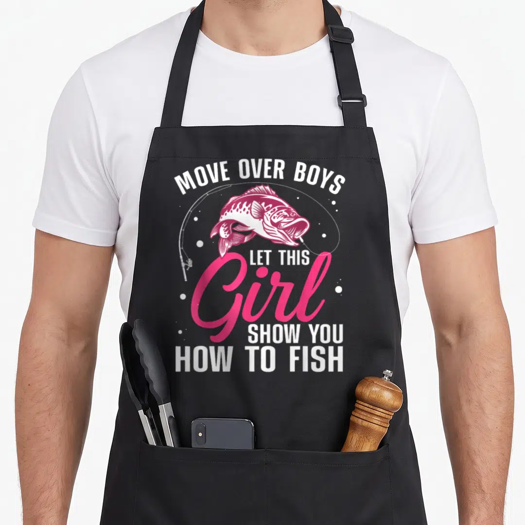 Cute fishing fisherman apron - Pink and white bass graphic with text Move Over Boys Let This Girl Show You How To Fish — shown on a black cotton canvas apron against a white background