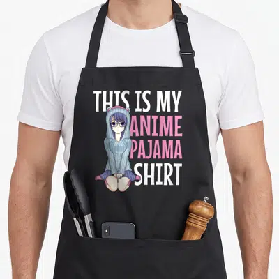Pajama anime apron - Cartoon girl in blue hoodie next to stacked white and pink text reading THIS IS MY ANIME PAJAMA — shown on a black cotton canvas apron against a white background
