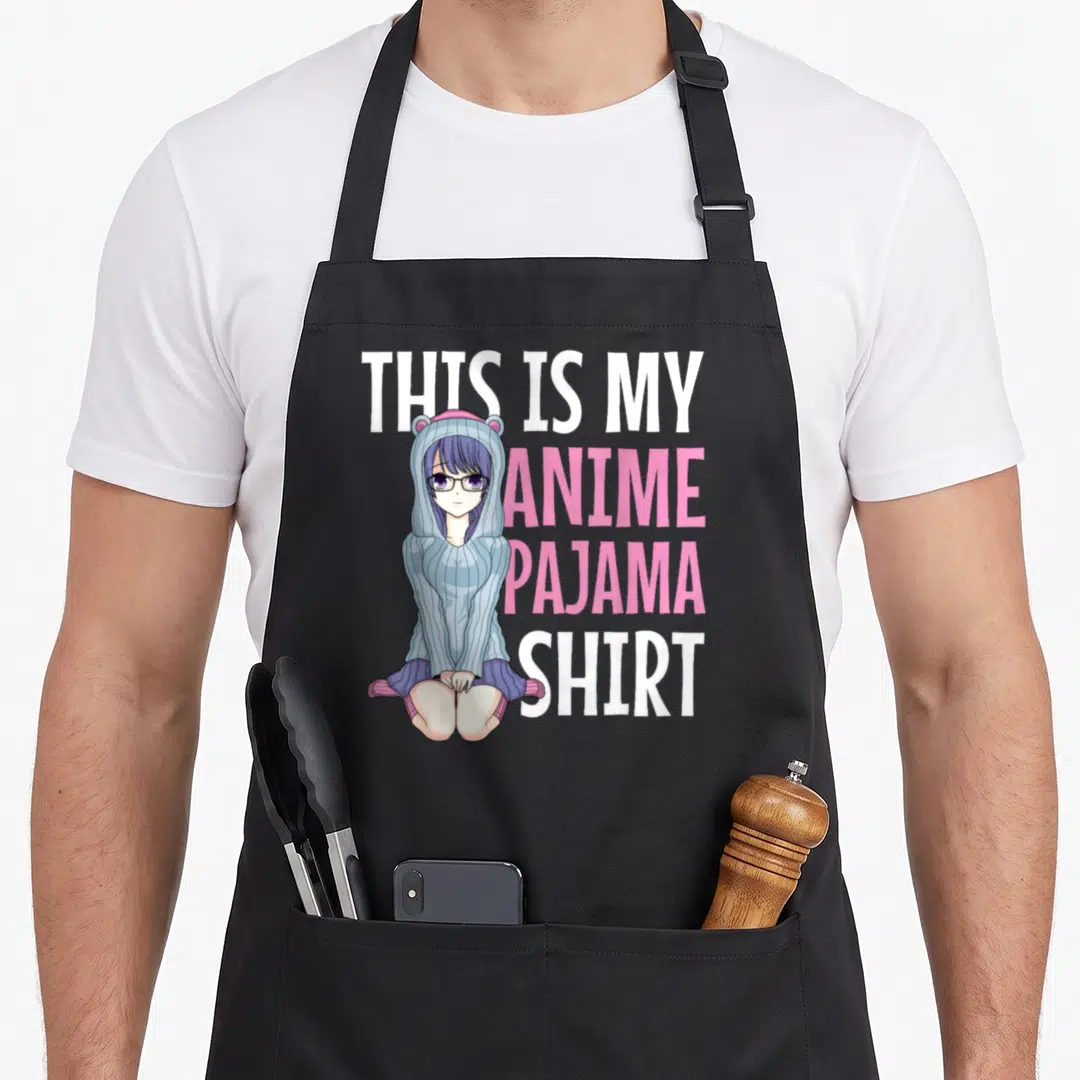 Pajama anime apron - Cartoon girl in blue hoodie next to stacked white and pink text reading THIS IS MY ANIME PAJAMA — shown on a black cotton canvas apron against a white background