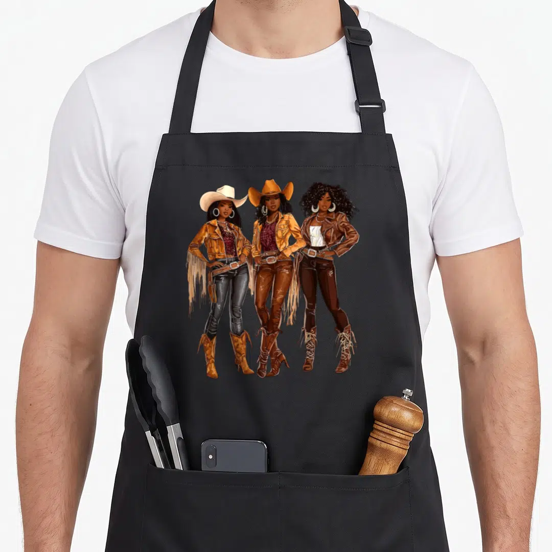 African western aprons - Three cartoon women in cowboy hats and fringe jackets standing in brown and tan — shown on a black cotton canvas apron against a white background