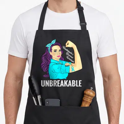 Hashimoto disease thyroid apron - Cartoon woman flexing arm with purple hair, blue shirt, and white text reading — shown on a black cotton canvas apron against a white background