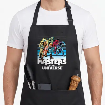 Fade universe apron - He-Man and villains with Castle Grayskull on blue stripes above stacked white text — shown on a black cotton canvas apron against a white background