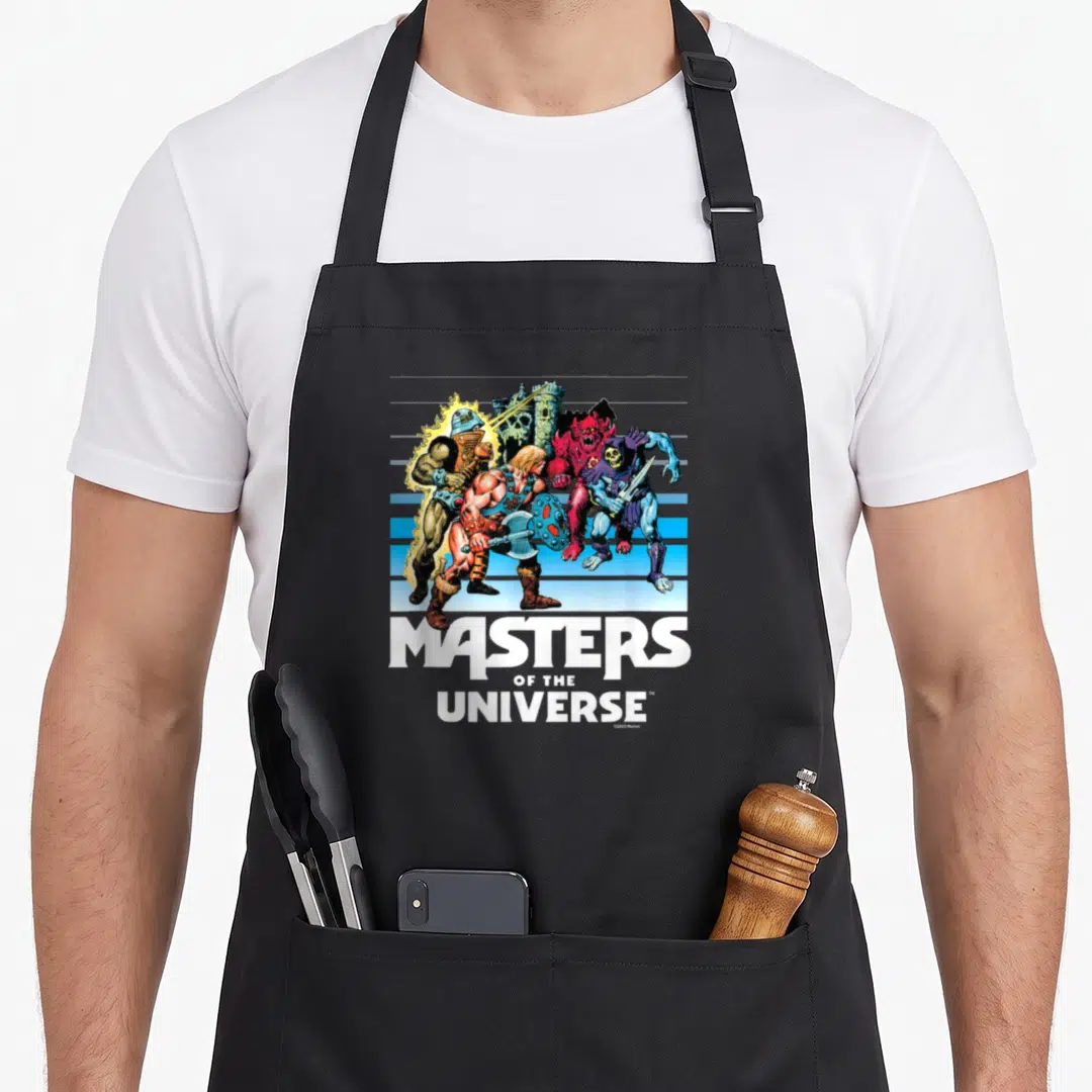 Fade universe apron - He-Man and villains with Castle Grayskull on blue stripes above stacked white text — shown on a black cotton canvas apron against a white background