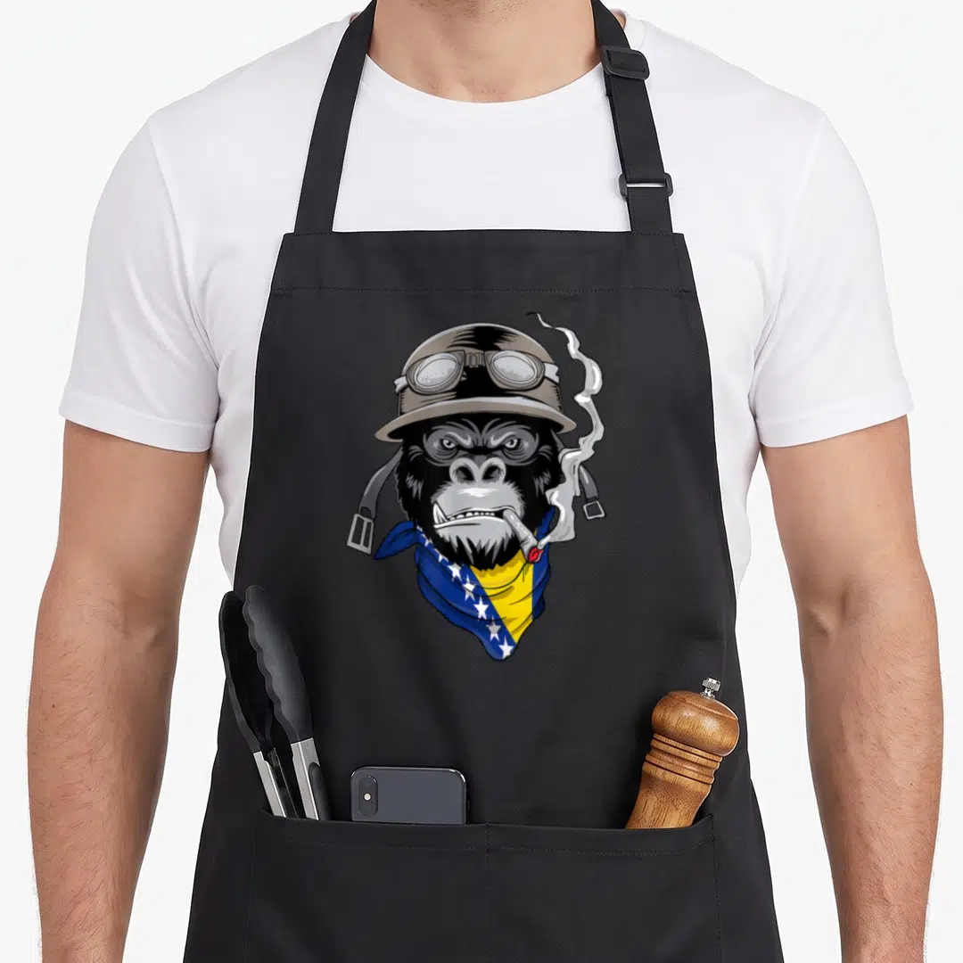 Bosnian motorcycle apron - Cartoon gorilla head wearing helmet goggles and blue yellow bandana with white stars — shown on a black cotton canvas apron against a white background