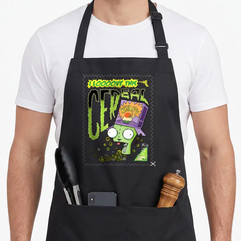 Invader cereal apron - Green monster wearing purple cereal box with I LOOOOVE THIS text and ray gun — shown on a black cotton canvas apron against a white background