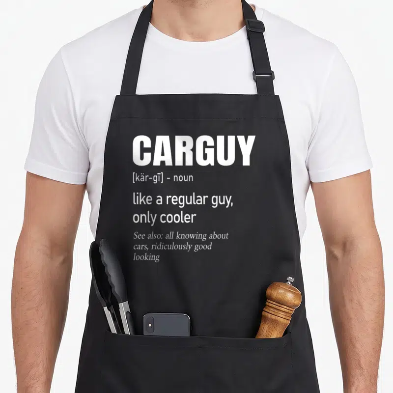 Car auto apron - White CARGUY dictionary definition text stacked on dark background with pocket details — shown on a black cotton canvas apron against a white background
