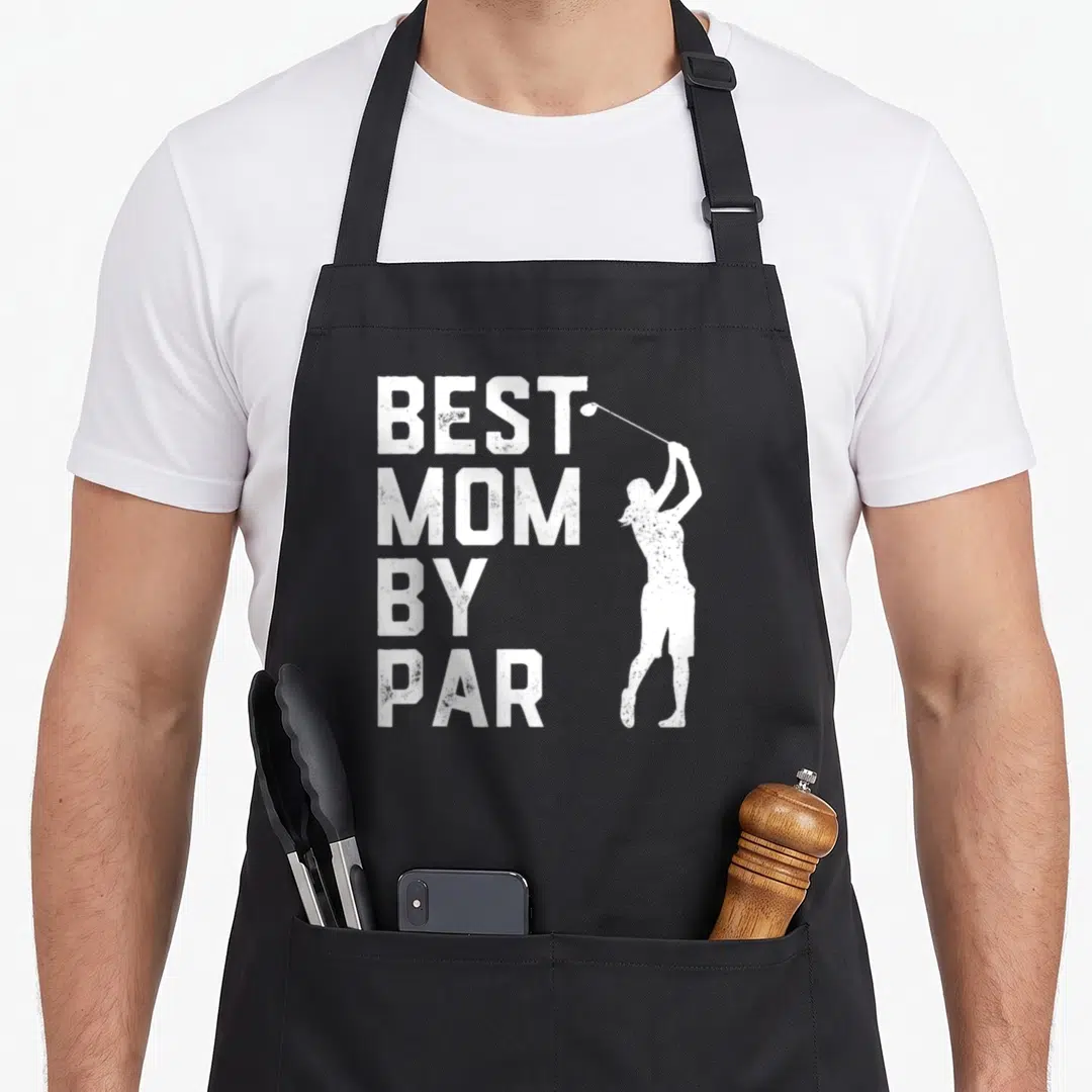 Mother golf apron - White distressed text BEST MOM BY PAR next to golfer swinging club silhouette — shown on a black cotton canvas apron against a white background